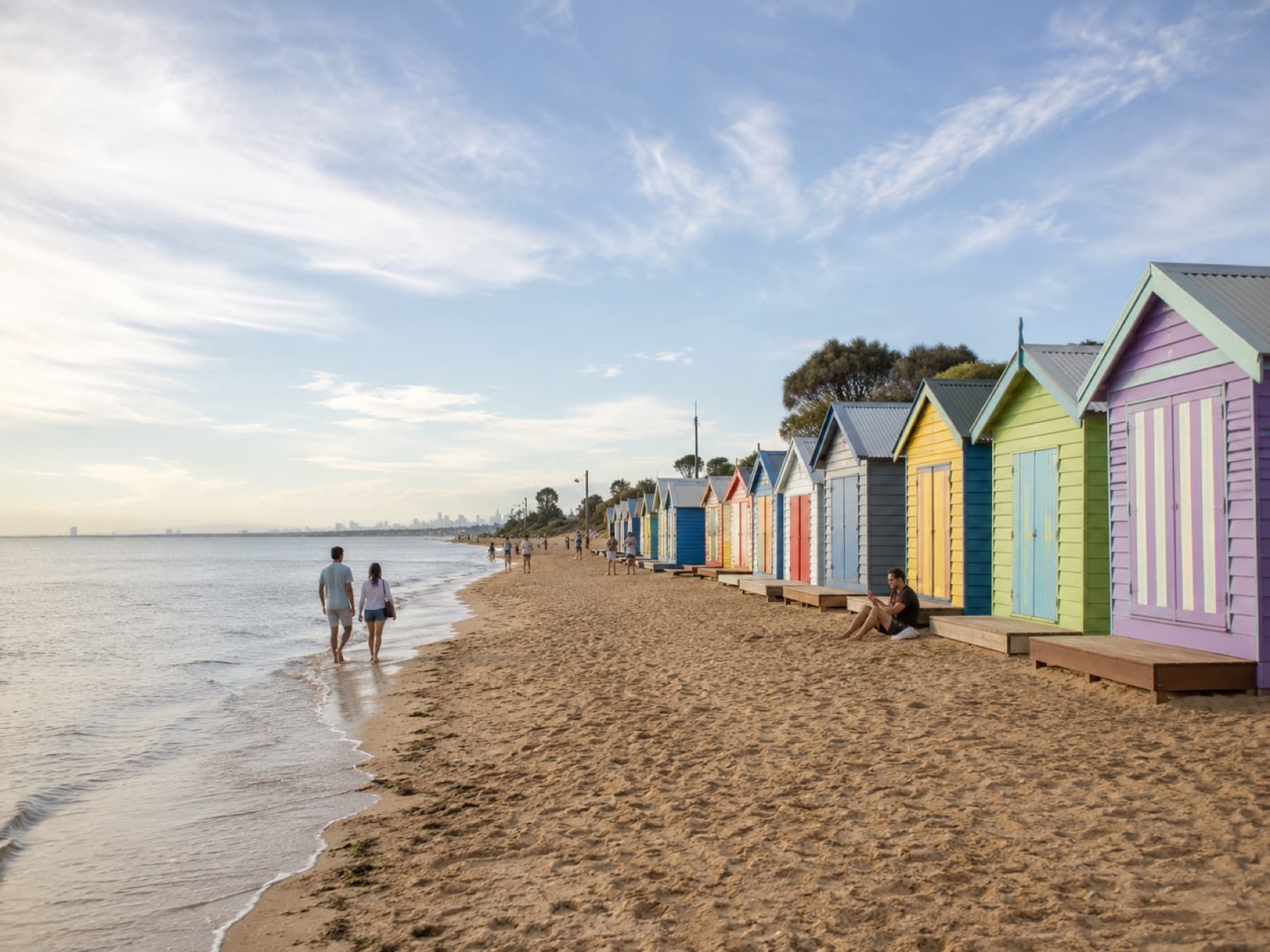 Brighton bathing boxes at golden hour with the city on the horizon
